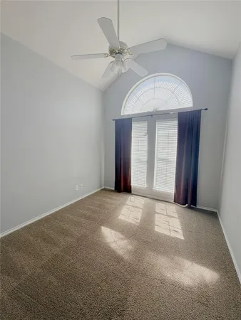 an empty room with a ceiling fan and window