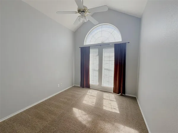 an empty room with a ceiling fan and a window