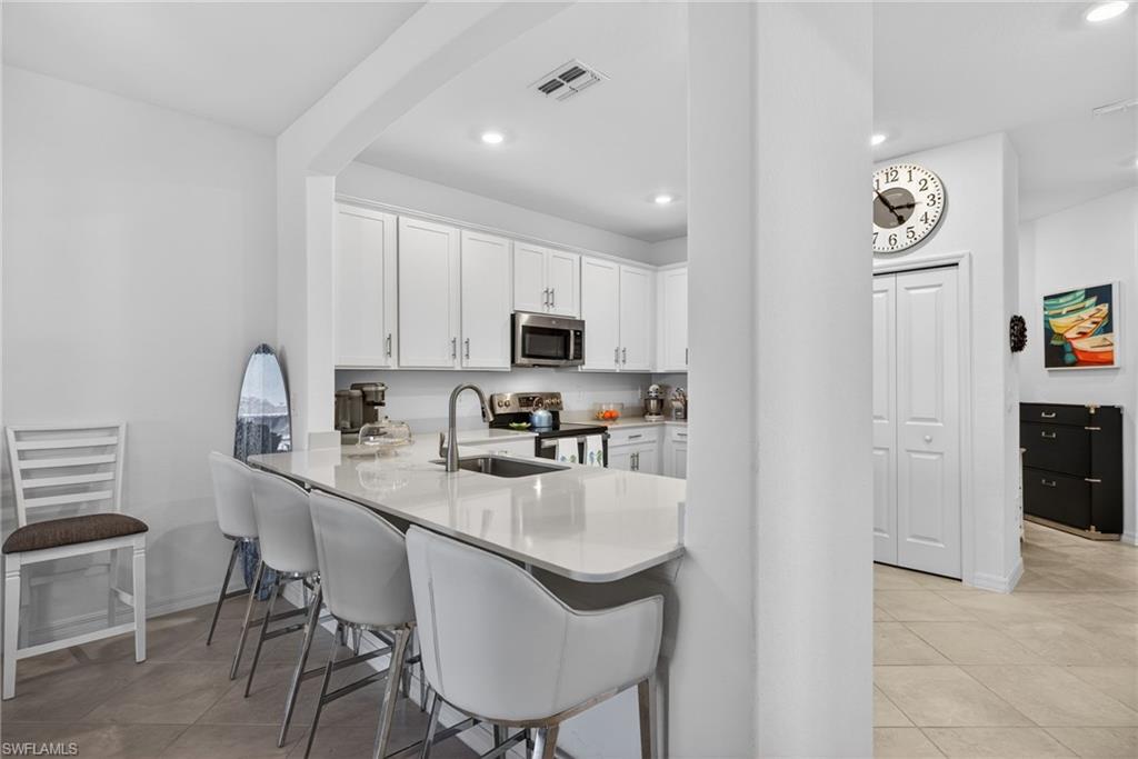 2323 Dragonfruit Way Naples, FL 34120 - Photo 8 of 32 a kitchen with stainless steel appliances granite countertop a table chairs sink and cabinets