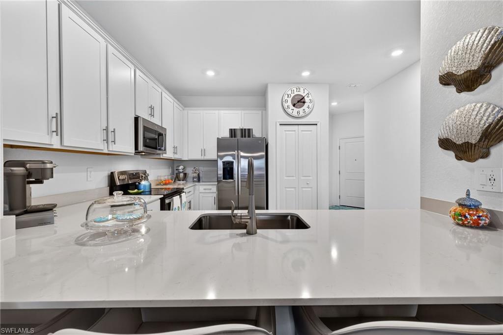 2323 Dragonfruit Way Naples, FL 34120 - Photo 10 of 32 a kitchen with stainless steel appliances granite countertop a sink a stove and a refrigerator