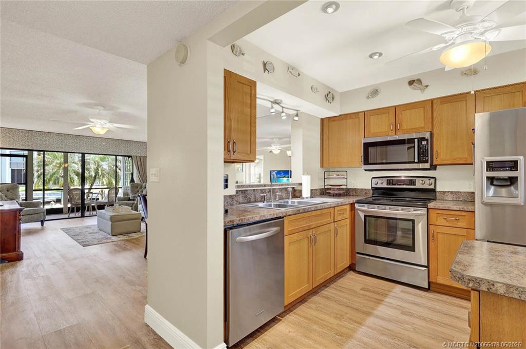 1950 Southwest Palm City Road, Unit 2102 Stuart, FL 34994 - Photo 12 of 55 a kitchen with stainless steel appliances granite countertop a stove top oven a sink dishwasher a dining table and chairs with wooden floor