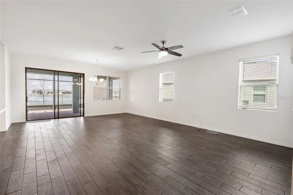 a view of an empty room with a window and wooden floor