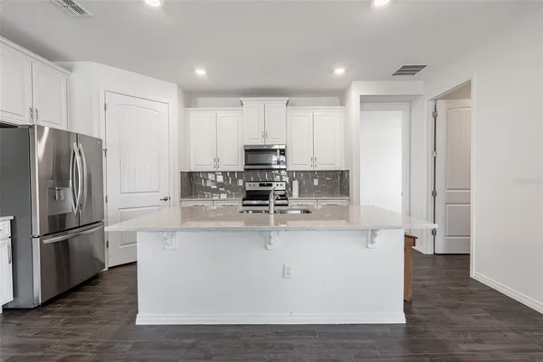 a view of kitchen with stainless steel appliances granite countertop a stove a refrigerator a sink and a microwave