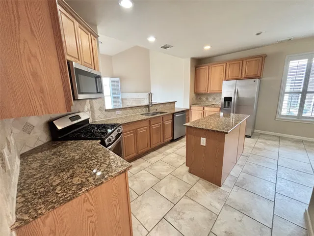 a kitchen with granite countertop a stove and a refrigerator