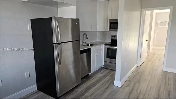 a kitchen with stainless steel appliances a refrigerator and wooden floor