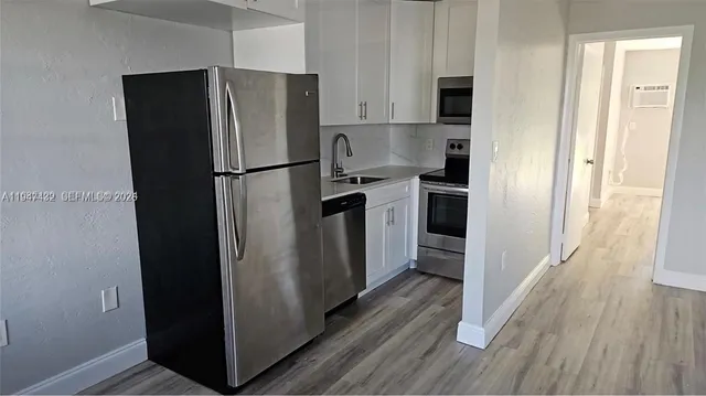 a kitchen with stainless steel appliances a refrigerator and wooden floor