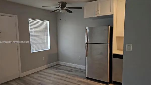 a view of empty room with wooden floor and fan