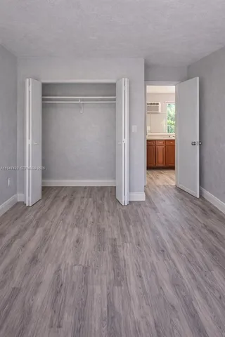 an empty room with wooden floor & windows and bathroom