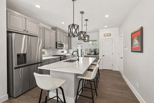 a kitchen with stainless steel appliances granite countertop a dining table chairs refrigerator and cabinets