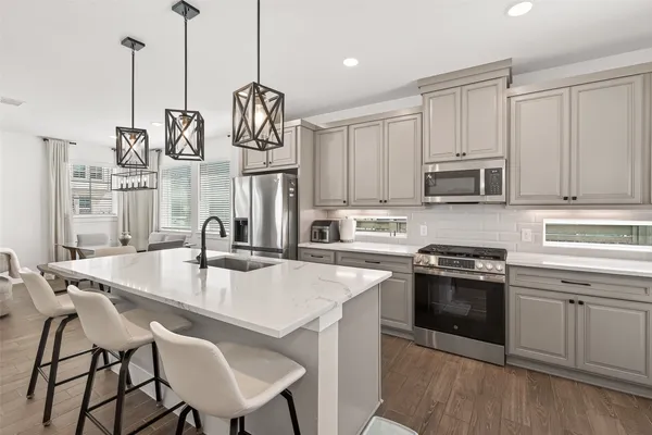 a kitchen with stainless steel appliances granite countertop a stove a sink a microwave and white cabinets