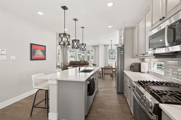 a kitchen with stainless steel appliances granite countertop a sink a stove and a wooden floors