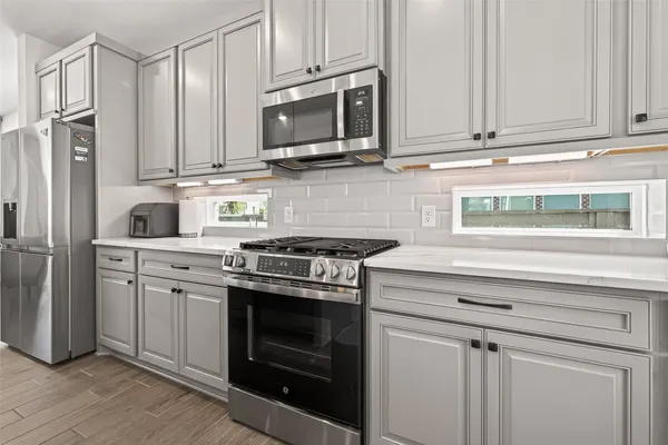 a kitchen with stainless steel appliances granite countertop a stove a microwave and a refrigerator