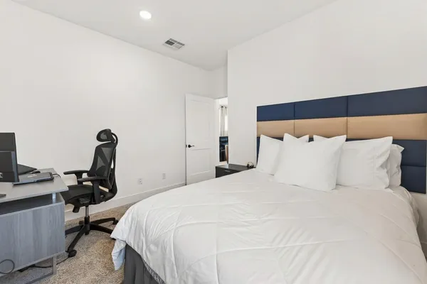 a bedroom with bed chair and computer on the desk