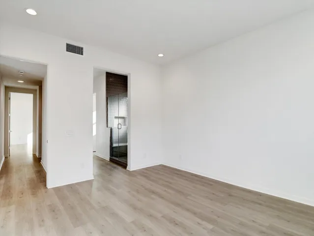a view of an empty room with wooden floor and closet
