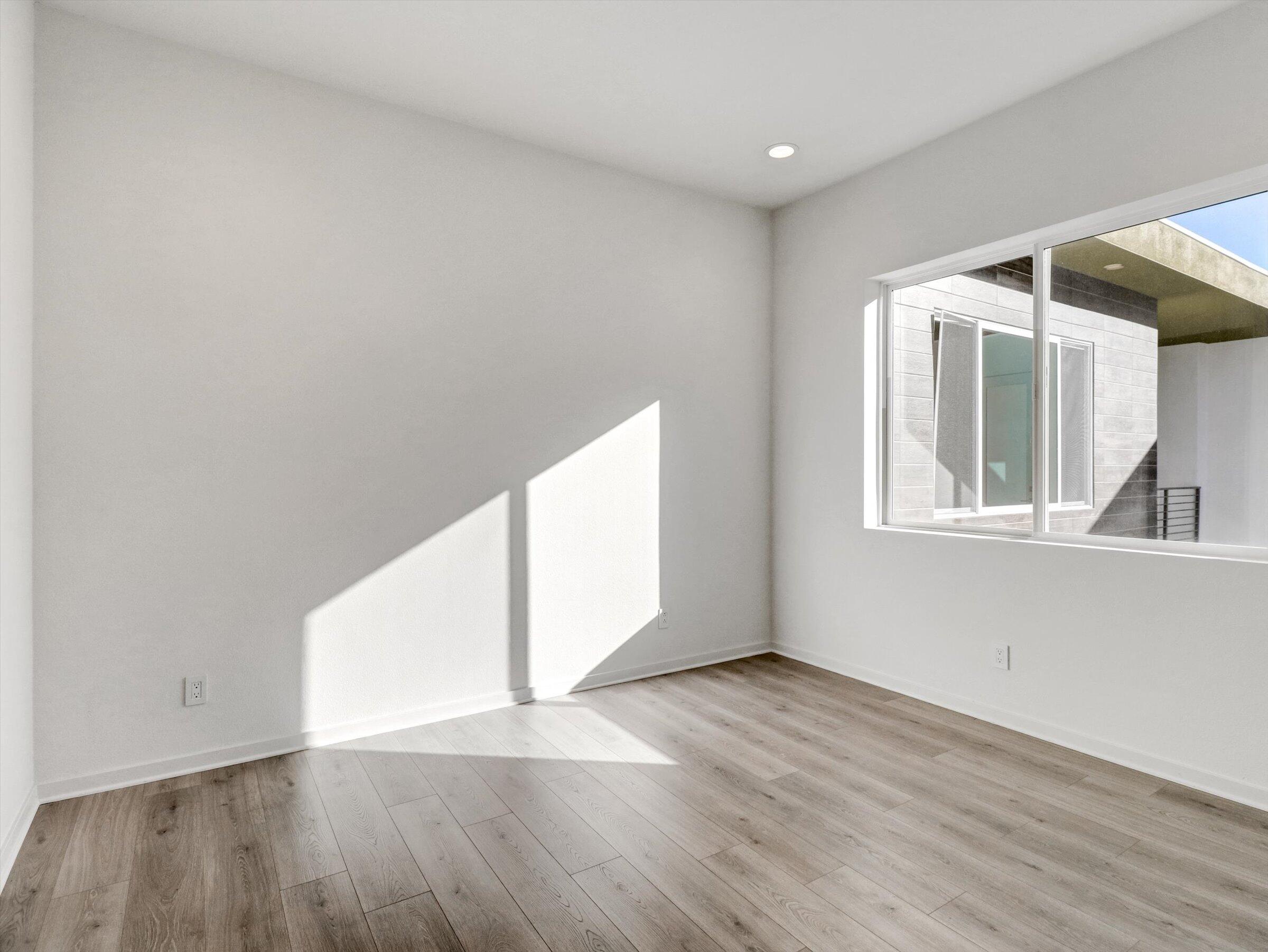 718 Obsidian Loop East, Unit 73 Palm Springs, CA 92264 - Photo 28 of 49 an empty room with wooden floor and windows