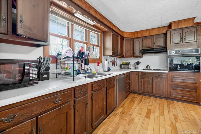 a kitchen with stainless steel appliances granite countertop a sink dishwasher stove and cabinets with wooden floor