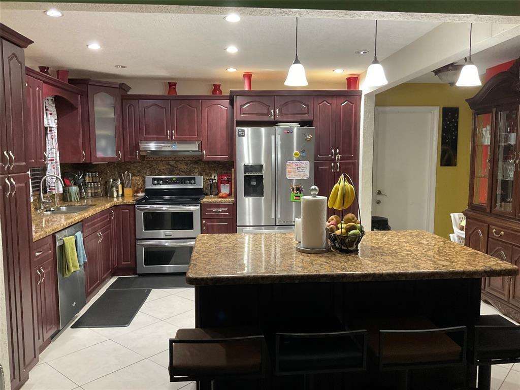 4770 Northwest 85th Avenue Lauderhill, FL 33351 - Photo 8 of 44 a kitchen with stainless steel appliances kitchen island granite countertop a refrigerator a stove top oven and a sink with wooden floor