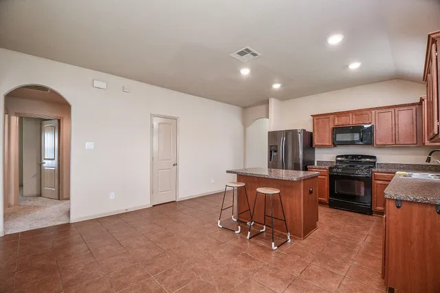 a kitchen with stainless steel appliances granite countertop a sink stove microwave and refrigerator