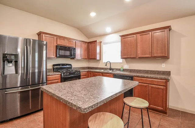 a kitchen with kitchen island granite countertop wooden cabinets and a stove top oven