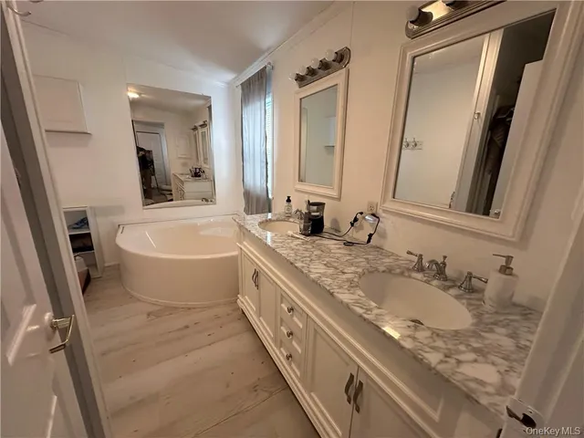 a bathroom with a granite countertop sink mirror vanity and bathtub