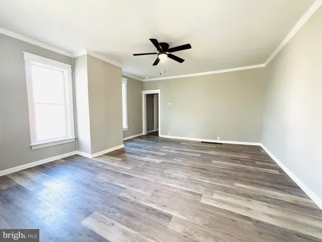 an empty room with wooden floor a ceiling fan and windows