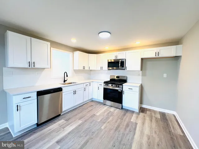 a kitchen with stainless steel appliances a refrigerator sink and white cabinets