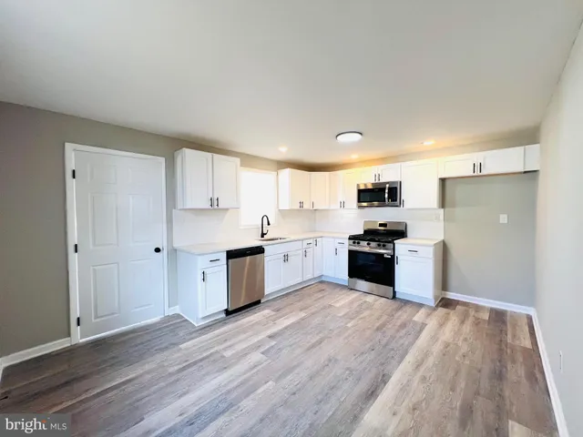 a large kitchen with a lot of kitchen island wooden floor and stainless steel appliances