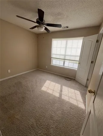 an empty room with windows and fan