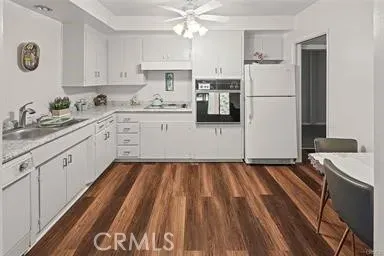 a kitchen with a refrigerator a stove a sink and white cabinets with wooden floor