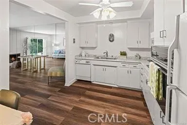 a kitchen with stainless steel appliances granite countertop a stove top oven a sink a dining table and chairs with wooden floor