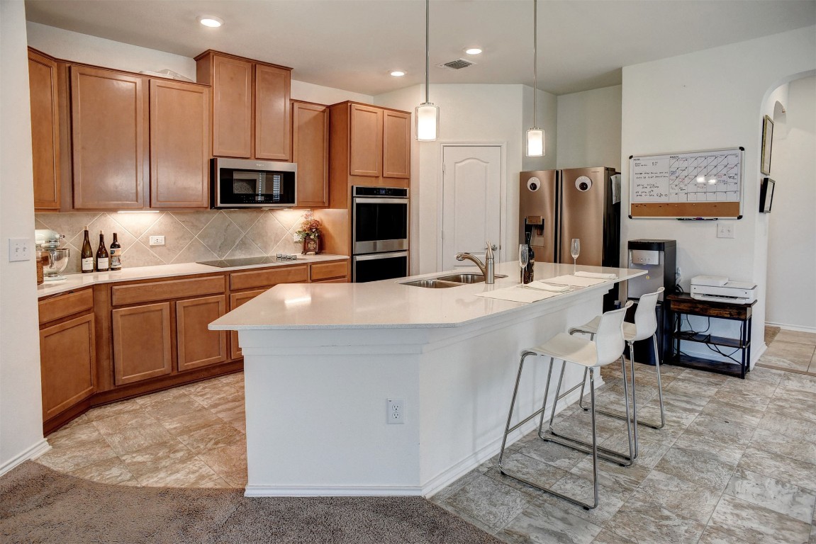 1928 Dragonfly Loop Bastrop, TX 78602 - Photo 2 of 32 a kitchen with stainless steel appliances kitchen island granite countertop a sink a stove a refrigerator and cabinets