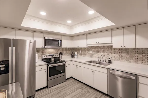 a kitchen with a sink white cabinets and stainless steel appliances