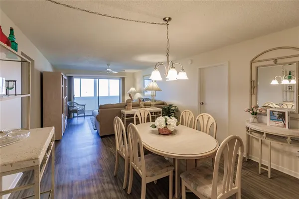 a view of a dining room and livingroom with furniture wooden floor a chandelier