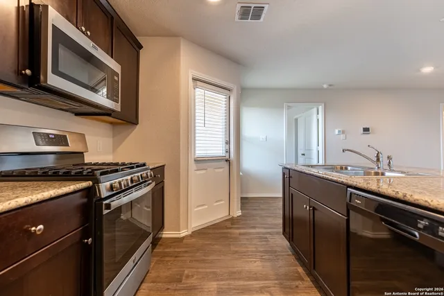 a kitchen with stainless steel appliances granite countertop a stove a sink and a microwave