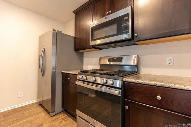 a kitchen with stainless steel appliances granite countertop a stove microwave and refrigerator