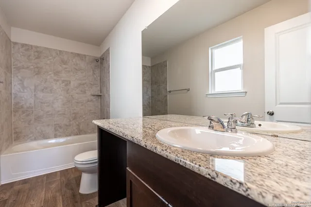 a bathroom with a granite countertop sink a toilet and bathtub