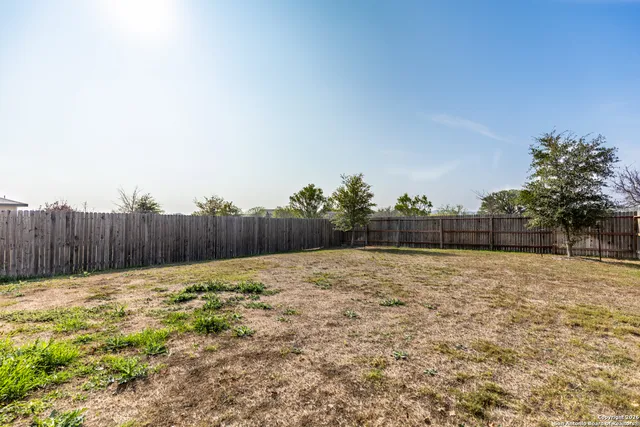 a view of a yard with wooden fence