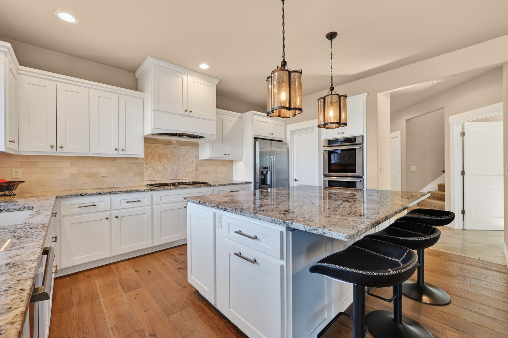 66355 Barr Road Bend, OR 97703 - Photo 17 of 56 a kitchen with stainless steel appliances kitchen island granite countertop a stove a sink and white cabinets with wooden floor
