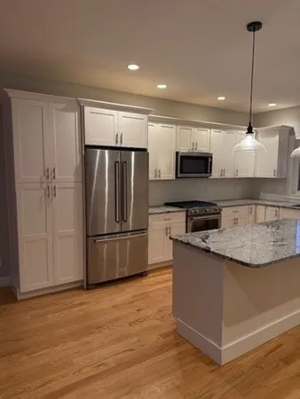 a kitchen with stainless steel appliances granite countertop a refrigerator a stove a sink and a microwave