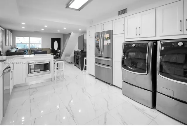 a kitchen with a refrigerator and white cabinets