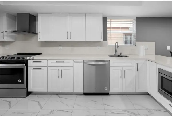 a kitchen with white cabinets and appliances