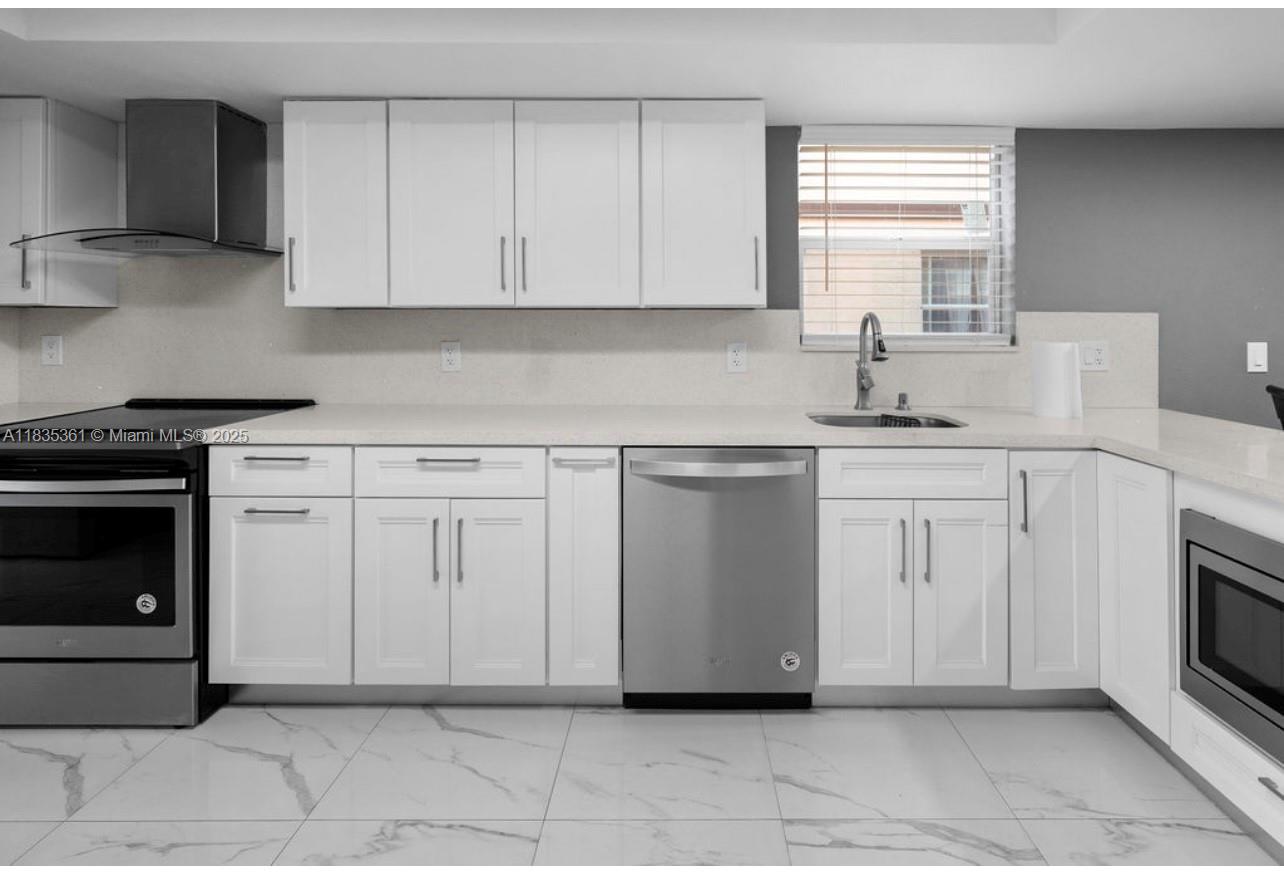 1158 West 41st Street, Unit 87 Hialeah, FL 33012 - Photo 9 of 16 a kitchen with white cabinets and appliances