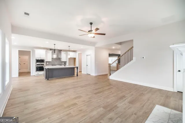 a large kitchen with stainless steel appliances granite countertop a sink and dishwasher a refrigerator with wooden floor