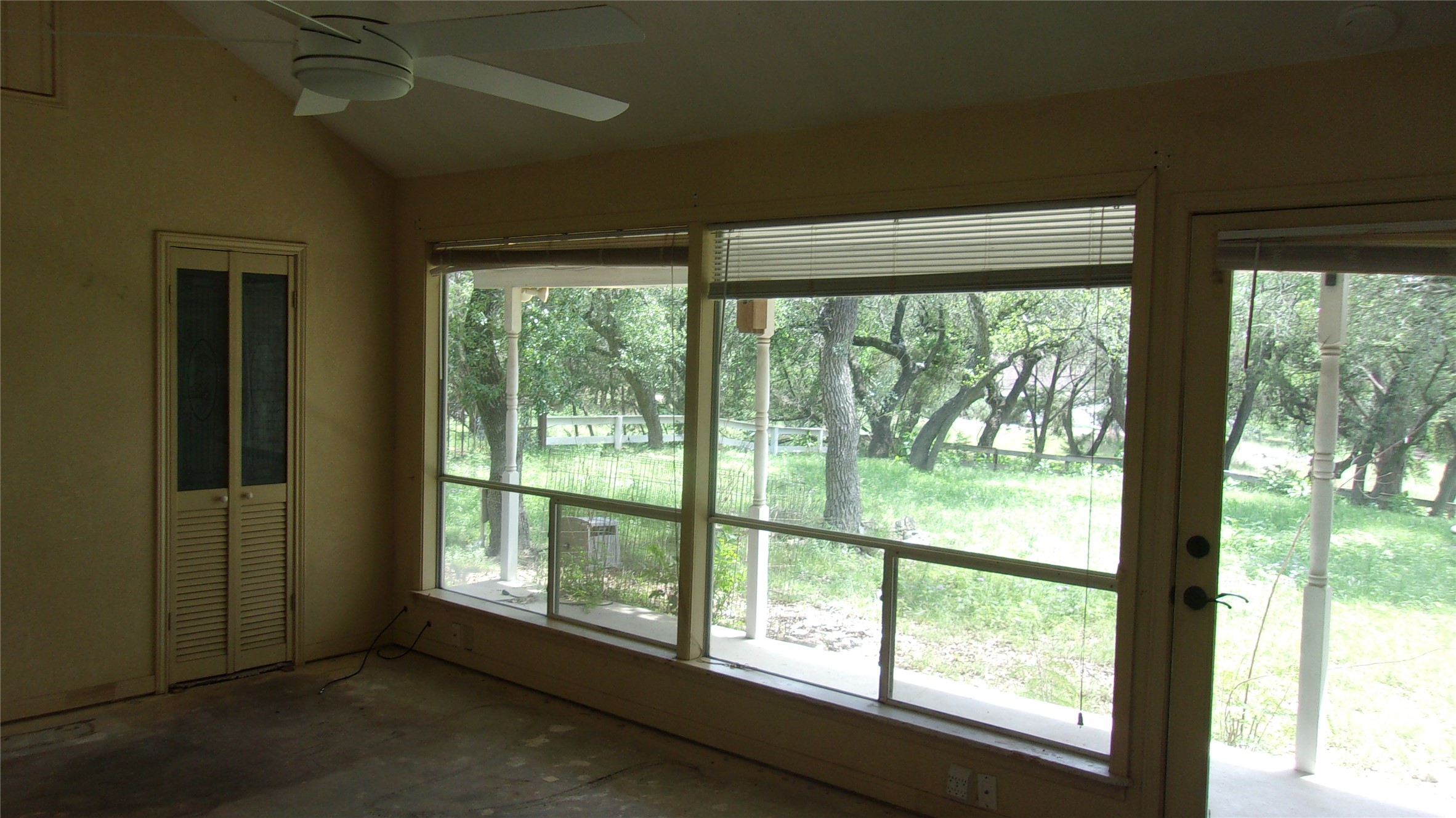 702 Cottonwood Creek Road Dripping Springs, TX 78620 - Photo 17 of 31 Vaulted ceiling with ceiling fan, large windows, sliding glass door, and louvered bifold doors