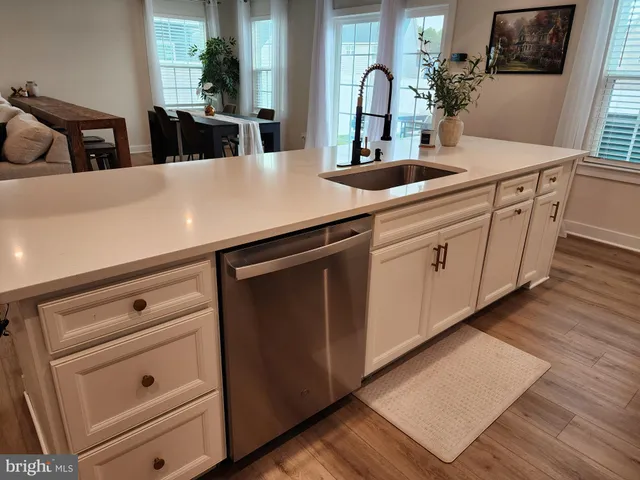 a view with a sink dishwasher and cabinets with wooden floor