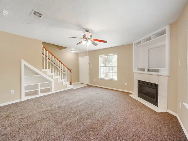 a view of an empty room with fireplace and a window