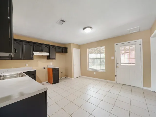 a kitchen with stainless steel appliances a sink a stove a refrigerator cabinets and a window