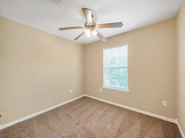 an empty room with a window and a fan