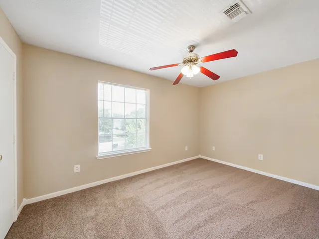 an empty room with ceiling fan and window