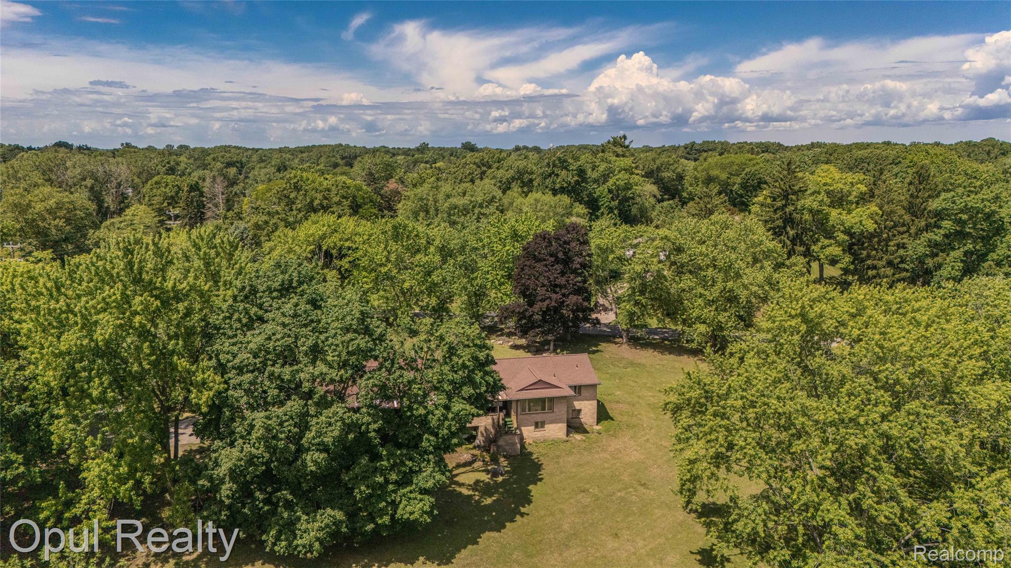6455 Norham Road Bloomfield Hills, MI 48301 - Photo 79 of 93 Expansive treed lot featuring a brown-roofed residence with light-toned siding and a surrounding grassy area